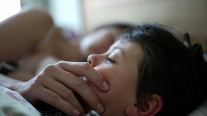 Mother gently touching her son's face in bed, intimate family moment, motherly affection, peaceful rest, nurturing care, early morning bonding, maternal love, close family connection, serene