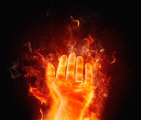 Conceptual outstretched hand on fire against a black background