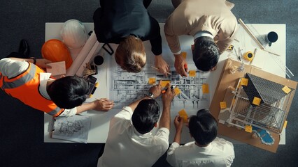 Top down view of skilled engineer team compare between blueprint and house plan. Aerial view of group of architect or designer discussing and point note to brainstorm about blueprint. Alimentation.