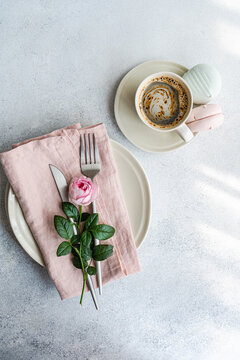 Overhead view of a place setting decorated with a pink rose and a cup of coffee with Zefir confectionery