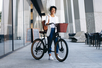 Smiling woman with bicycle and backpack in urban European city