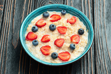 Homemade breakfast . Oatmeal with milk and berries . Top view