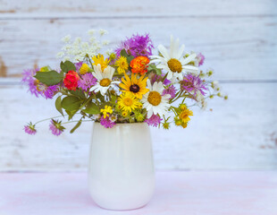 Beautiful Wild Summer Flowers in a Small Vase on wooden background 