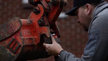 Construction worker attaches bucket to backhoe excavtor bucket