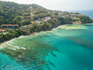 View of a coastal town with turquoise waters and lush green hills, featuring buildings