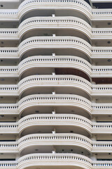 Abstract architecture background. Close-up of high-rise building facade with repetitive pattern of curved balconies, showcasing architectural design in Bangkok city, Thailand. Vertical orientation