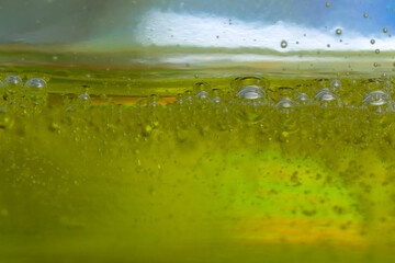 Air bubbles in thick yellow water in clear glass