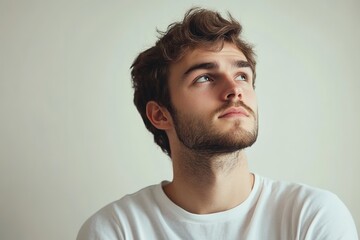Fototapeta premium Young man looking up, hopeful expression, beard, contemplative.