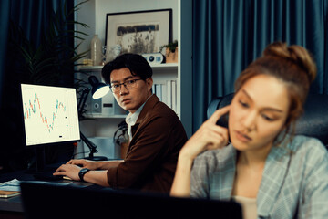 Stressful businesswoman looking at computer stock exchange via email with coworker working at back...