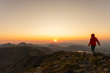 Fototapeta premium A person is walking on a mountain top at sunset