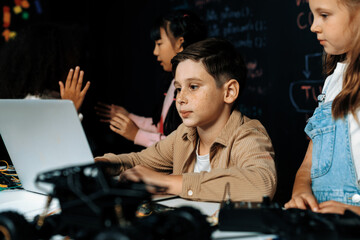 In classroom student in STEM class learning about coding robotics car. Brown shirt Schoolboy and...