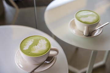 Matcha latte with delicate latte art and its reflection in a cozy mirror in a Prague coffee shop
