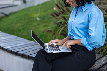 Close up of woman in blue shirt working on laptop