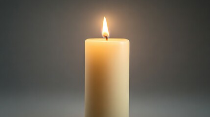   Close-up of a lit candle on a gray background with illumination from above