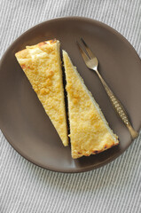 Cottage cheese pie on a brown plate top view. Two segments of fresh homemade pastry top view vertical image