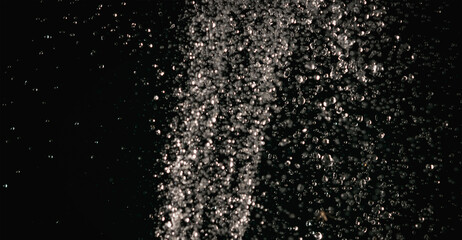 Splashes of water pouring from a hose in the dark