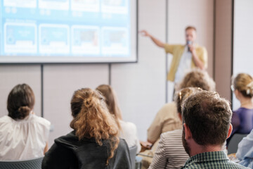 Group of people engaged in a professional seminar with speaker presenting at front. Audience...