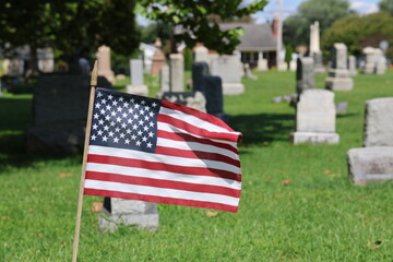 American flag in cemetery among graves and gravestones tombstones sunny day