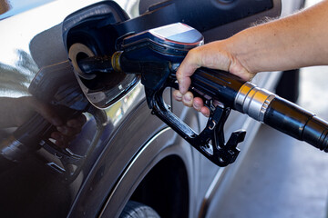 Fototapeta premium a man is putting gas in his car, his hand near the car,