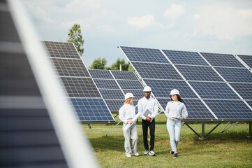 Portrait of engineers standing outside near solar panels. Three workers, two woman and one men