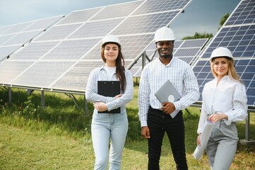 Group of multi ethnic people and safety helmets staring at solar farm.