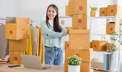 Portrait Asian female SME retail store owner in her home office with parcel box background. Fashion designer Startup small business SME concept.