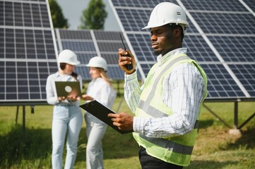 Group of multi ethnic people and safety helmets staring at solar farm.