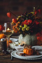 Cozy festive holiday table decor for home family Thanksgiving dinner. Traditional event, elegant natural decoration. Wooden rustic table, countryside style. Burning candles, floral centrepiece pumpkin