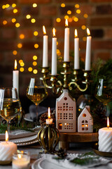 Elegant decor for Christmas family dinner. Center piece with burning candles, vintage chandelier. Zero waste eco-friendly reusable home decoration, fir tree branches. Cozy atmosphere, wooden furniture