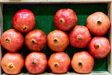 Fresh, ripe pomegranates are carefully and evenly displayed on the counter in the store.
