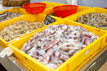 Seafood assortment in an Asian supermarket. Fresh squid and shrimp of different sizes in plastic boxes for self-service.