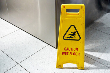A yellow floor folding sign that draws attention to a freshly washed slippery floor.