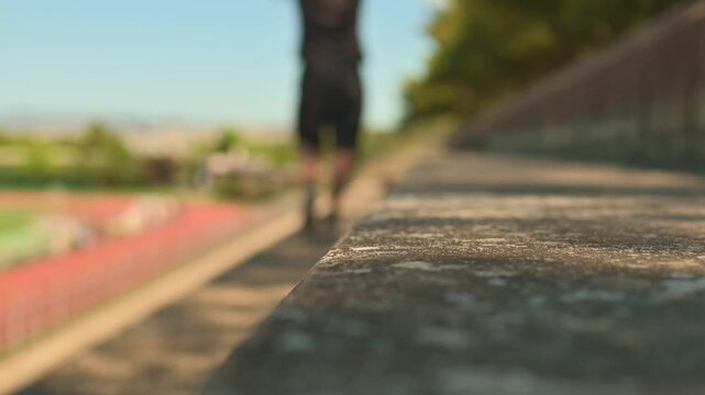 Static shot footage with shallow depth of field shows a man working out by going up and down stairs at the tribunes of a stadium.