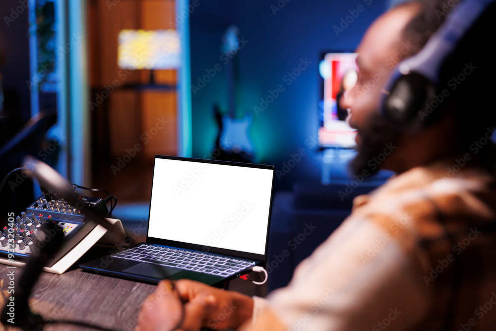 Poster selective focus on laptop displaying an isolated chromakey mockup template while black man uses podc