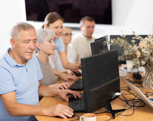 Elderly man learns to use computer in group at master class