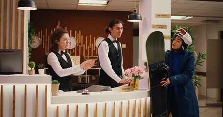 At mountain resort, woman asks about amenities as she is impatient to begin skiing practice down...