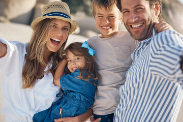 Family, portrait and selfie on beach for travel, holiday and bonding together in summer while carrying. Mom, dad and kids by ocean for fun trip, vacation and social media with happiness and memory