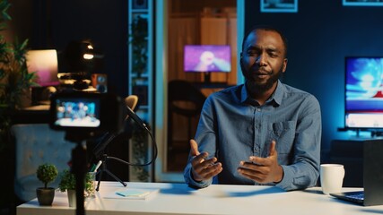 Happy content creator using professional recording devices in cozy studio to film video intro for online streaming platforms. Influencer greets fanbase, talking about today topic