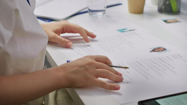 HR staff going through the selection process phase of the recruitment activity, choosing the best applicant based on their qualifications in the resume. Recruiters seeking talent. Camera A.