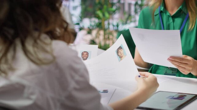 Human resources staff evaluating candidates resume in the selection process, reviewing all applicants after job interview in order to hire the right person. Recruiters seeking personnel. Camera A.