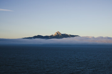 Sunset  illuminating mountains above a soft sea of clouds and the ocean