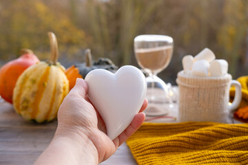 white heart against cozy autumn background, hot cocoa with marshmallows, pumpkins and autumn leaves, creating warm and inviting atmosphere, tranquility motivation