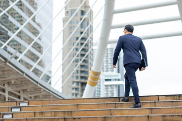 Asian businessman office worker employee holding digital tablet walking up the stairs at office district in the city. Business people working corporate business financial and communication in the city