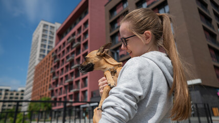 Young Caucasian woman holding a small dog in her hands. 