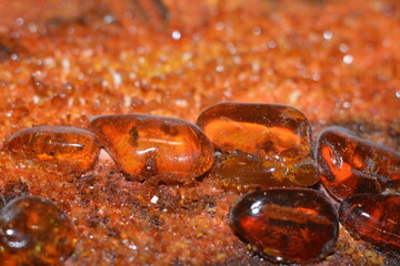 Amber processed stones against a background of small crushed ambers