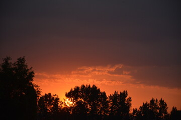 Bright red evening sun setting below the horizon
