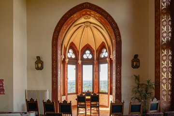 An ornate room in Drachenfels Castle features arched windows and antique decor. This Gothic-inspired space offers a glimpse into the castle's history and architectural detail.