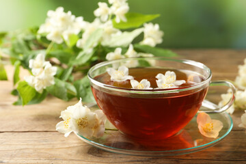 Hot jasmine tea in cup and flowers on wooden table