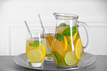 Freshly made lemonade with mint in jug and glasses on light grey table
