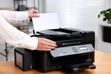 Woman using modern printer at workplace indoors, closeup
